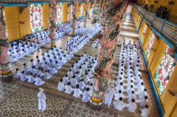 Tay Ninh, 96km northwest of Ho Chi Minh City is home to the “Holy See” of the once powerful Cao Dai religious sect. Founded in 1926 and based on messages revealed in séances to it’s founder, Ngo Minh Chieu, Cao Dai incorporates elements of Buddhism, Hinduism, Taoism, Confucianism and Spiritualism. It’s pantheon of deities includes Buddha, Confucius, Jesus Christ, Mohammed, Joan of Arc, Sun Yat Sen and Victor Hugo amongst others. The clergy is based on the Roman Catholic hierarchy and headed by a ‘pope’.
In the 1930’s the sect became increasingly nationalistic and organised it’s own militias, running Tay Ninh province as an almost independent feudal state. They were involved in revolts against the French before and during WW2, co-operating with the Japanese and then allying themselves to the Viet Minh in the early years of the post war struggle against the French administration. A pragmatic group they switched sides, giving nominal allegiance to the Emperor Bao Dai and the French, whilst still retaining anti-French sentiment. The Cao Daists provided the basis for the ‘Third Force’ in Graham Greene’s classic novel, “The Quiet American” and by 1956 boasted an army of about 20 000 troops.
During the second Indochina war (known to the Vietnamese as the ‘American war’) they were allied to the South Vietnamese government and refused to aid the Viet Cong, a point not lost to the Communists who redistributed their lands and executed a four of their leaders after taking power. It wasn’t until 1985 and the Cao Dai had been thoroughly pacified were they allowed to once again take control of their ‘Holy See’ and some 400 temples across Vietnam. Today it is estimated that there are some 2 – 3 million followers world wide.
All Cao Dai temples hold religious ceremonies every six hours starting at midnight during which the clergy and lay people perform an elaborate, regimented ritual which includes offerings of incense, tea, alcohol, frui