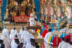 Tay Ninh, 96km northwest of Ho Chi Minh City is home to the “Holy See” of the once powerful Cao Dai religious sect. Founded in 1926 and based on messages revealed in séances to it’s founder, Ngo Minh Chieu, Cao Dai incorporates elements of Buddhism, Hinduism, Taoism, Confucianism and Spiritualism. It’s pantheon of deities includes Buddha, Confucius, Jesus Christ, Mohammed, Joan of Arc, Sun Yat Sen and Victor Hugo amongst others. The clergy is based on the Roman Catholic hierarchy and headed by a ‘pope’.
In the 1930’s the sect became increasingly nationalistic and organised it’s own militias, running Tay Ninh province as an almost independent feudal state. They were involved in revolts against the French before and during WW2, co-operating with the Japanese and then allying themselves to the Viet Minh in the early years of the post war struggle against the French administration. A pragmatic group they switched sides, giving nominal allegiance to the Emperor Bao Dai and the French, whilst still retaining anti-French sentiment. The Cao Daists provided the basis for the ‘Third Force’ in Graham Greene’s classic novel, “The Quiet American” and by 1956 boasted an army of about 20 000 troops.
During the second Indochina war (known to the Vietnamese as the ‘American war’) they were allied to the South Vietnamese government and refused to aid the Viet Cong, a point not lost to the Communists who redistributed their lands and executed a four of their leaders after taking power. It wasn’t until 1985 and the Cao Dai had been thoroughly pacified were they allowed to once again take control of their ‘Holy See’ and some 400 temples across Vietnam. Today it is estimated that there are some 2 – 3 million followers world wide.
All Cao Dai temples hold religious ceremonies every six hours starting at midnight during which the clergy and lay people perform an elaborate, regimented ritual which includes offerings of incense, tea, alcohol, frui