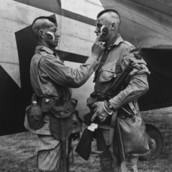 Paratroopers Clarence C. Ware and Charles R. Plaudo from HQ Co. 506 PIR. 101 Abn Div, painting each other's faces on the afternoon of June 5, 1944. This phot was printed in Stars and Stripes, and helped form the legend of "The Filthy Thirteen.