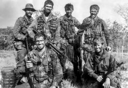 Nui Dat. SAS Hill, South Vietnam. 1971-04-08. Members of patrol Two Five, 'F' Troop, 2 Squadron, Special Air Service (SAS) at Nadzab LZ after returning from their second patrol. The patrol of nine days was from 30 March until 8 May 1971. Left to right, back row: Corporal Ian Rasmussen (patrol 2IC), Trooper Don Barnby (patrol signaller), Trooper Dennis Bird (patrol scout), 2nd Lieutenant Brian Russell (patrol commander). Front row: Trooper Bill Nisbett (rifleman), John Deakin (USN-SEAL attached).
AWM Accession Number: P00966.084 SASR Don Barnby Vietnam SAS
