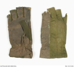 US tropical pattern gloves : Trooper D R Barnby, 2 Squadron, Special Air Service Regiment.
Description
Two right hand, olive green, US issued tropical gloves with the tops of all fingers removed. Two thirds of the top surface of the gloves is made from an olive green nylon mesh, with the index finger being entirely covered with Nomex. This Nomex extends up the entire length of the upper glove to the cuff. The palms of the gloves are made from a worn Nomex material.
The stitching for one of the glove's right thumb is slightly frayed, and has come undone, with the other one entirely missing. The glove with the missing thumb also has a blue-green coloured number 9 hand written midway along the top of the glove above the index finger. This glove is also of a slightly lighter coloured olive green colour than the other. Around the cuff of the gloves is zig-zag stitching which slightly blouses the gloves.
History / Summary
These gloves were modified and worn on operations, to help protect the wearer's hands from the harsh conditions of the jungle and when using weapons. They also provided a form of camouflage for the exposed hands of the wearer, Trooper Don Barnby.
AWM Accession Number: REL/14214.004 SASR Don Barnby Vietnam SAS