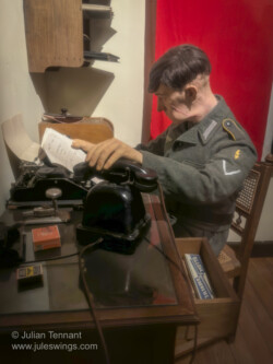Interrogation display. The caption reads. "September 2, 1944 - At the Kommandantur of Bastogne, the Germans are nervous. The Allied forces are advancing rapidly and members of the resistance are committing more and more acts of sabotage. Close to the railroad, a person has been arrested by a German patrol. Roughly treated by the German soldiers who captured him, the alleged member of the Resistance is presented to a superior officer before being interrogated by the Gestapo. 101st Airborne Museum Bastogne