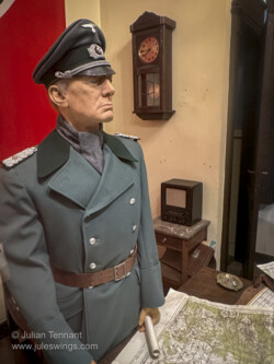 Interrogation display. The caption reads. "September 2, 1944 - At the Kommandantur of Bastogne, the Germans are nervous. The Allied forces are advancing rapidly and members of the resistance are committing more and more acts of sabotage. Close to the railroad, a person has been arrested by a German patrol. Roughly treated by the German soldiers who captured him, the alleged member of the Resistance is presented to a superior officer before being interrogated by the Gestapo. 101st Airborne Museum Bastogne