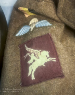 Detail from a British battledress uniform featuring the Belgian national flag, British parachutist wing and printed Airborne Division 'Pegasus' patch.