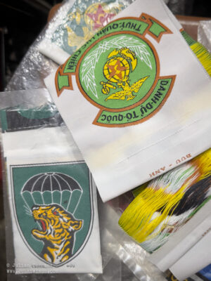 Dan Sinh War Surplus Market. March 2026. FAKE ARVN MIKE Force and RVN Marine Corps patches. Made using the 'bevo' style, these patches can be distinquished from the silk originals as they are polyester and the reverse shows the threads tracing across the whole of the patch surface, not just the insignia portion as per the originals. Photo: Julian Tennant Dan Sinh War Surplus Market